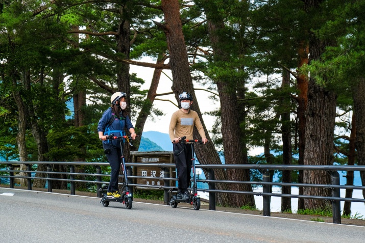 田沢湖の湖畔を電動キックボードで移動する写真